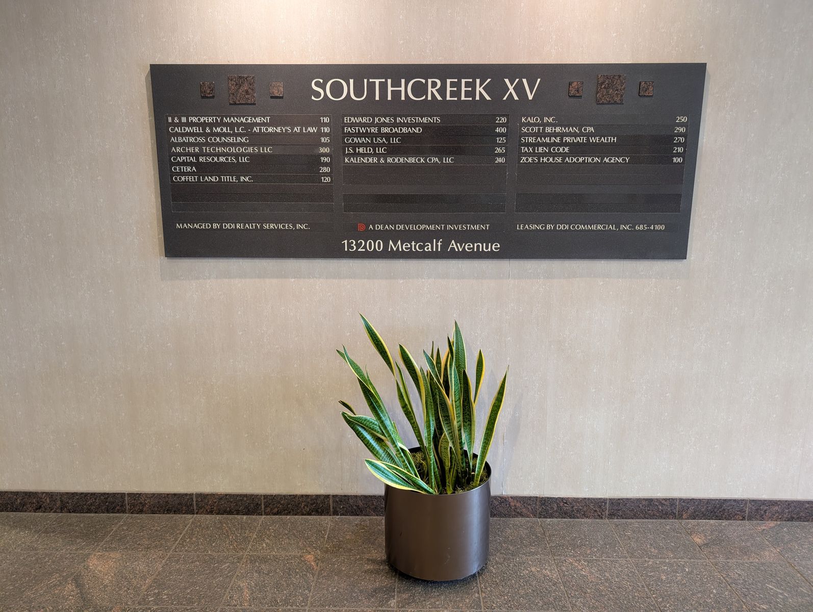 Southcreek XV lobby directory listing Albatross Counseling in Suite 105, with a potted plant beneath it