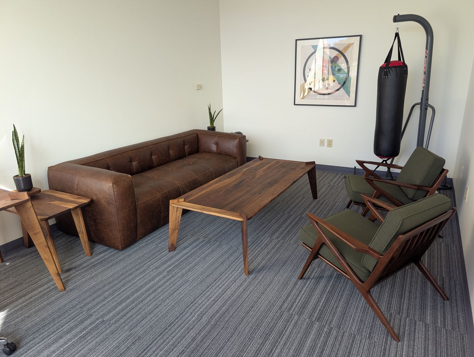 Counseling office with a leather couch, walnut coffee table, two green armchairs, and a heavy bag